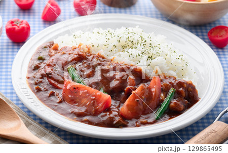 ほかほかと香り立つトマトカレーと白ごはんの盛り付け　サラダ付き家庭料理の食卓イメージ 129865495
