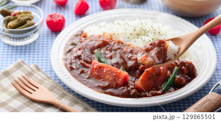 ほかほかと香り立つトマトカレーと白ごはんの盛り付け　サラダ付き家庭料理の食卓イメージ 129865501