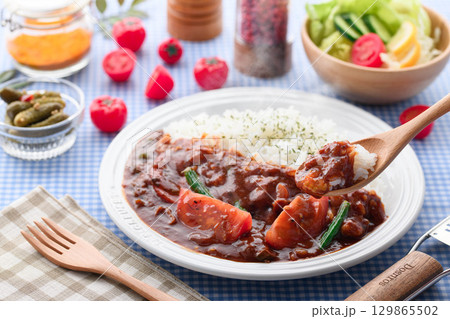 ほかほかと香り立つトマトカレーと白ごはんの盛り付け　サラダ付き家庭料理の食卓イメージ 129865502