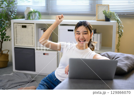 Happy female freelancer cheering after achieving online work milestone 129866070