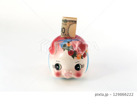 豚の貯金箱に紙幣を入れる 豚の貯金箱に紙幣を入れる 129866222