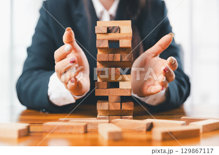 Business risk control concept, Businesswoman protect wooden block fall to planning and strategy in risk to business alternative and prevent. investment insurance business. 129867117