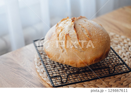Homemade sourdough bread cooling on a rack on a rustic wooden table Homemade sourdough bread cooling on a rack on a rustic wooden table 129867611