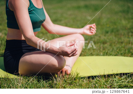 Calm young woman meditating outdoors in lotus position, practicing yoga and mindfulness for mental balance Calm young woman meditating outdoors in lotus position, practicing yoga and mindfulness for mental balance 129867641