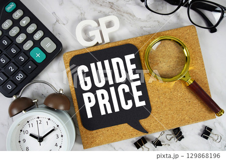 GP Guide Price text with Calculator, alarm clock and magnifying glass on marble background 129868196