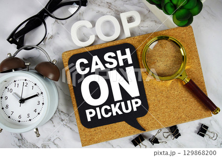 COP Cash On Pickup text with alarm clock and magnifying glass on marble background COP Cash On Pickup text with alarm clock and magnifying glass on marble background 129868200