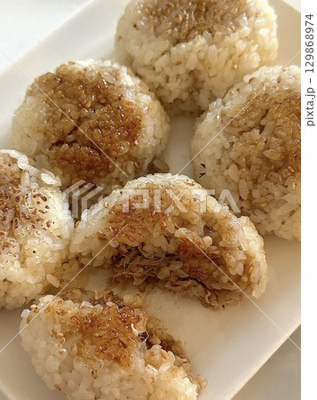 Soft and savory onigiri filled with delicious ingredients, wrapped in crisp nori, offering a perfect balance of comforting flavors and satisfying textures in every convenient, handheld bite. 129868974