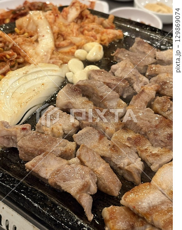 Juicy grilled samgyeopsal paired with and tangy, sizzling kimchi, creating a perfect balance of rich, earthy, and spicy flavors in every delicious, mouthwatering bite. 129869074