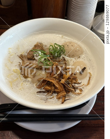 A steaming bowl of ramen with rich broth, tender noodles, sliced pork, boiled egg, nori, and fresh green onions. A comforting and flavorful Japanese classic. 129869077
