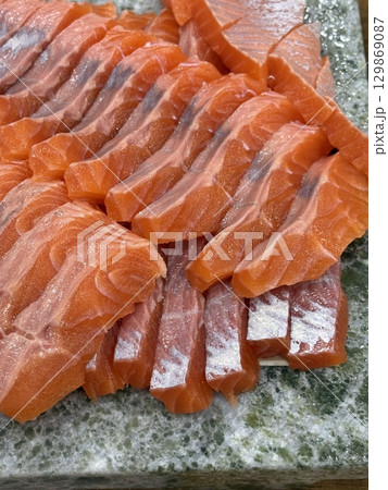 Fresh and delicate sashimi slices, beautifully presented with vibrant colors and perfect cuts. This traditional Japanese delicacy highlights the pure flavors of premium seafood. 129869087