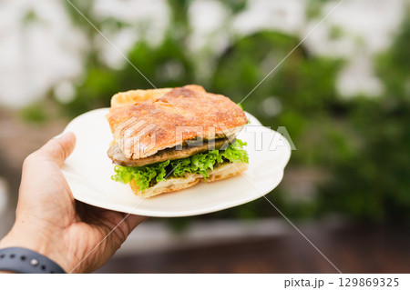 Man bringing fresh focaccia sandwiches on a white plate. 129869325