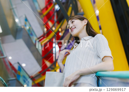 デパートのエスカレーターに乗る女性 129869917