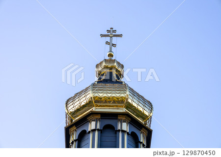 A magnificent golden dome topped with a cross reaches towards the sky, symbolizing faith and history. The structure stands out in the urban landscape A magnificent golden dome topped with a cross reaches towards the sky, symbolizing faith and history. The structure stands out in the urban landscape 129870450