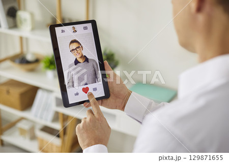Person using smartphone dating app to like a profile with heart icon closeup 129871655