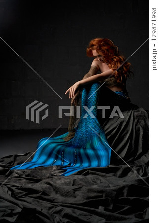 Lonely mermaid sitting on the rock with her head down Lonely mermaid sitting on the rock with her head down 129871998