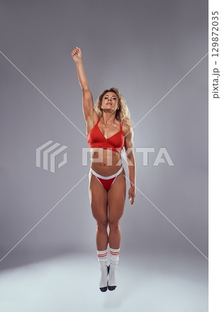 Fitness muscular superwoman flying up to the sky 129872035