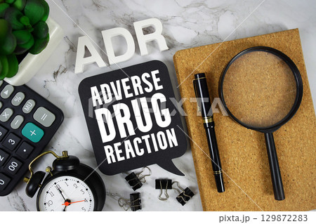 ADR Adverse Drug Reaction text with Calculator, alarm clock and magnifying glass on marble background 129872283