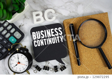 BC Business Continuity text with Calculator, alarm clock and magnifying glass on marble background BC Business Continuity text with Calculator, alarm clock and magnifying glass on marble background 129872295