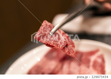トングで持ち上げた但馬牛の美しい霜降り肉 トングで持ち上げた但馬牛の美しい霜降り肉 129873434