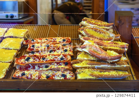 Hot sandwiches with melted cheese, sausages, pizza toppings displayed at festive food stall. Concept of Christmas cheese sandwich, quick meal, winter comfort street food Hot sandwiches with melted cheese, sausages, pizza toppings displayed at festive food stall. Concept of Christmas cheese sandwich, quick meal, winter comfort street food 129874411