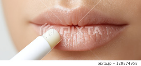 Lip balm application on close up face showing beauty and makeup routine with foundation blending for smooth cosmetic care and natural look 129874958