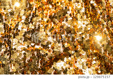 Close up of golden sequins fabric texture with shining light. 129875157