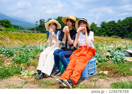 夏の高原で麦わら帽子をかぶった日本人の女の子たちが白いおにぎりを持って座る 夏の高原で麦わら帽子をかぶった日本人の女の子たちが白いおにぎりを持って座る 129876789