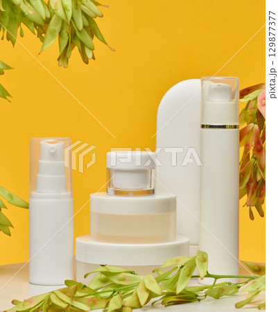 Set of white plastic cosmetic packaging without brand on yellow background. Container for beauty industry, skin care and advertising Set of white plastic cosmetic packaging without brand on yellow background. Container for beauty industry, skin care and advertising 129877377