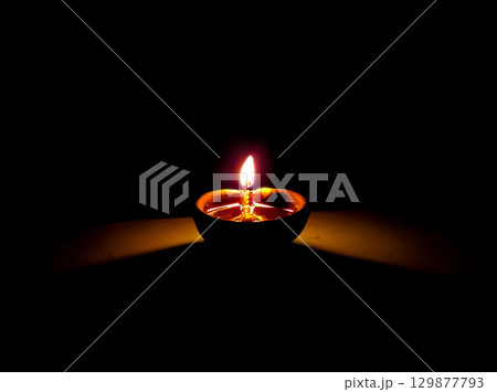 Single Clay Oil Lamp Glowing in Darkness Single Clay Oil Lamp Glowing in Darkness 129877793