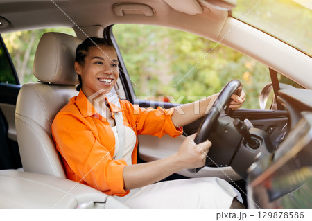 Joyful young black woman laughing while driving her car Joyful young black woman laughing while driving her car 129878586