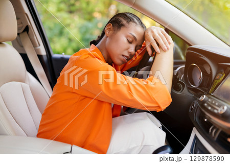 Exhausted young black woman resting and sleeping on steering wheel inside car Exhausted young black woman resting and sleeping on steering wheel inside car 129878590