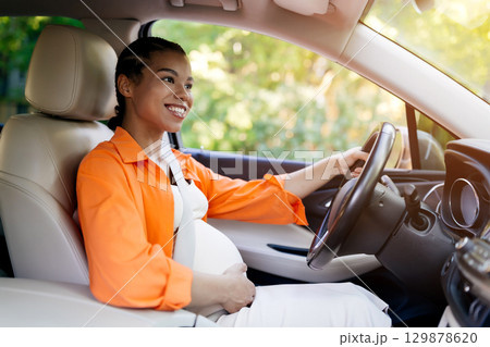Happy black pregnant woman driving car in sunlight, smiling and enjoying ride Happy black pregnant woman driving car in sunlight, smiling and enjoying ride 129878620