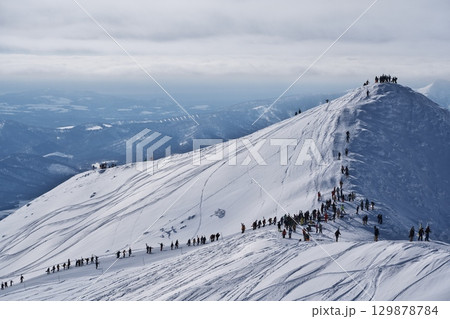ニセコ東急 グラン・ヒラフのゲレンデからスキー場管理区域外を登る人々 129878784