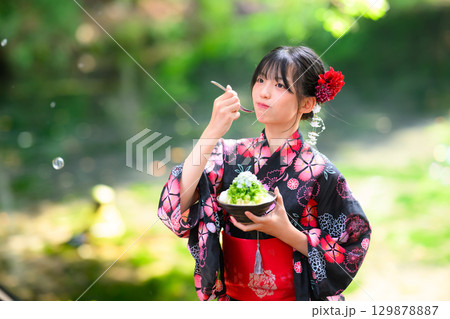 高原の湖で浴衣を着た日本人の小学生の女の子がかき氷を食べている風景 高原の湖で浴衣を着た日本人の小学生の女の子がかき氷を食べている風景 129878887