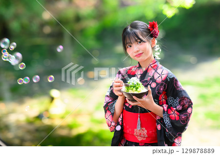 高原の湖で浴衣を着た日本人の小学生の女の子がかき氷を食べている風景 129878889