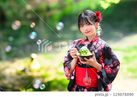高原の湖で浴衣を着た日本人の小学生の女の子がかき氷を食べている風景 129878890