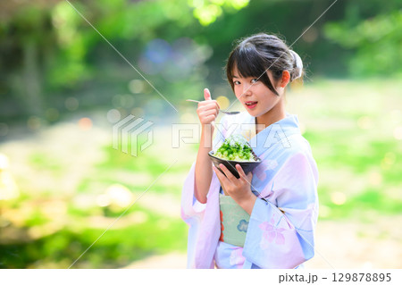 高原の湖で浴衣を着た日本人の小学生の女の子がかき氷を食べている風景 129878895