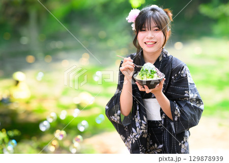 夏の高原の湖で浴衣を着た日本人の小学生の女の子がかき氷を食べている風景 129878939
