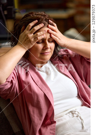 Brunette woman holding head with hands in pain Brunette woman holding head with hands in pain 129879373