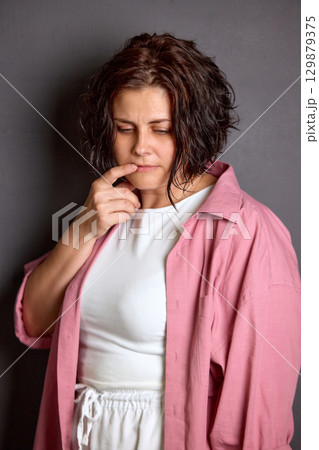 Brunette woman in pink shirt thinking with pensive face Brunette woman in pink shirt thinking with pensive face 129879375