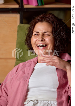 Brunette woman laughing with open mouth in cheerful mood Brunette woman laughing with open mouth in cheerful mood 129879376