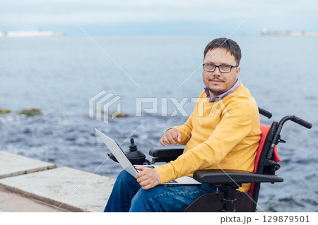 businessman on a wheelchair at a window uses smartphone businessman on a wheelchair at a window uses smartphone 129879501