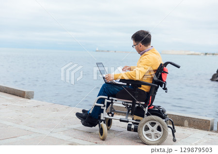 businessman on a wheelchair at a window uses smartphone 4k 129879503