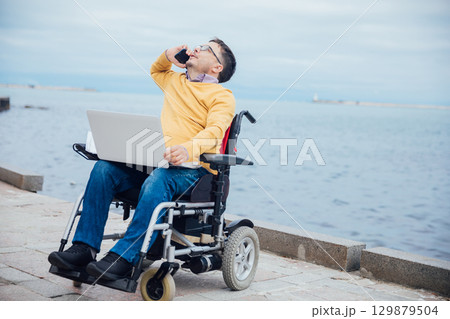 businessman on a wheelchair at a window uses smartphone 4k 129879504