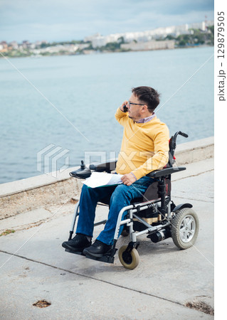 businessman on a wheelchair at a window uses smartphone 4k 129879505