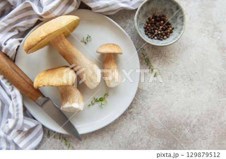 Fresh porcini mushrooms on plate with knife and peppercorns ready for cooking 129879512