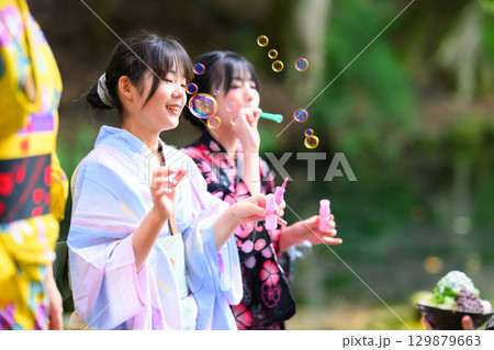 浴衣を着た日本人の小学生の女の子がシャボン玉で遊ぶ夏の風景 浴衣を着た日本人の小学生の女の子がシャボン玉で遊ぶ夏の風景 129879663