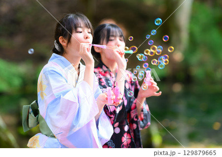 浴衣を着た日本人の小学生の女の子がシャボン玉で遊ぶ夏の風景 浴衣を着た日本人の小学生の女の子がシャボン玉で遊ぶ夏の風景 129879665
