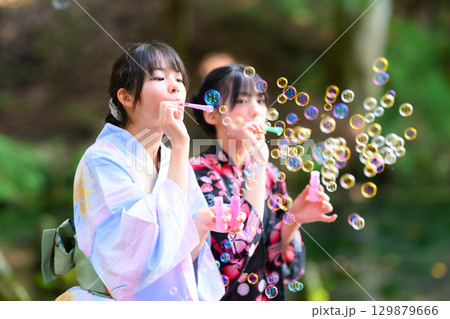 浴衣を着た日本人の小学生の女の子がシャボン玉で遊ぶ夏の風景 浴衣を着た日本人の小学生の女の子がシャボン玉で遊ぶ夏の風景 129879666
