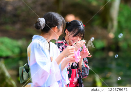 浴衣を着た日本人の小学生の女の子がシャボン玉で遊ぶ夏の風景 浴衣を着た日本人の小学生の女の子がシャボン玉で遊ぶ夏の風景 129879671